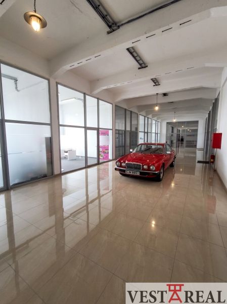 Offices with a red car, floor with wooden decor, glass partitions.