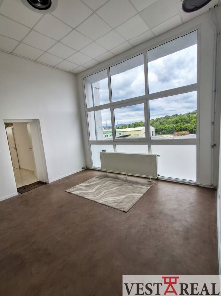 An office with a large window, wooden decor flooring, and heating.