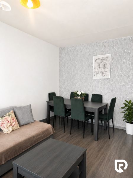 Dining area with a dark table and chairs in a three-room apartment with a wooden decor floor.