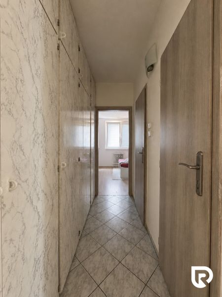 A hallway with built-in wardrobes and tiles leads to a room in a 3-room apartment.
