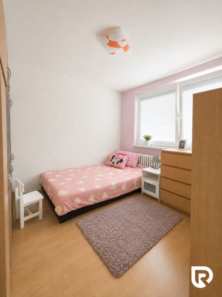 A room in a 3-room apartment with pink bed linens, a wardrobe, and a wooden decor floor.