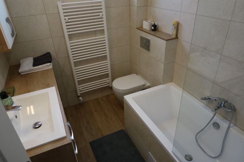 A bathroom in a 2-room apartment with a bathtub, a sink, and a floor with a wooden decor.