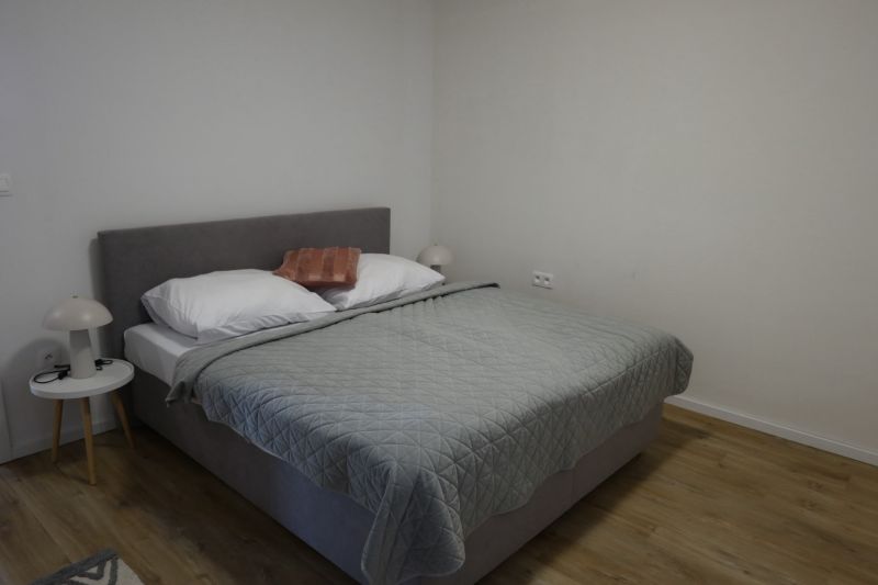 A bedroom in a two-room apartment with a wooden decor floor and a bed.