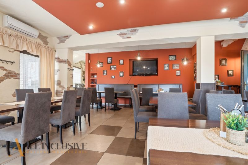 Restaurant interior with an orange wall, seating, and decorations in dining spaces.