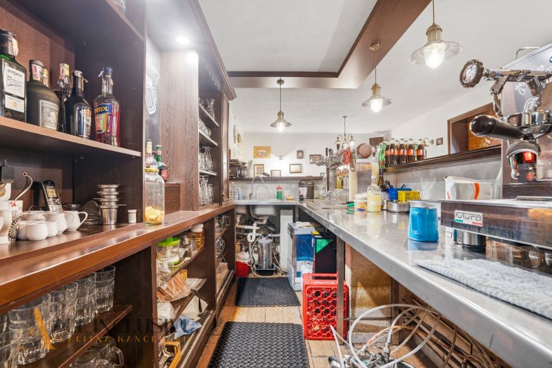 Interior of a gastro space with a bar and drinks on shelves, floor with wooden decor.