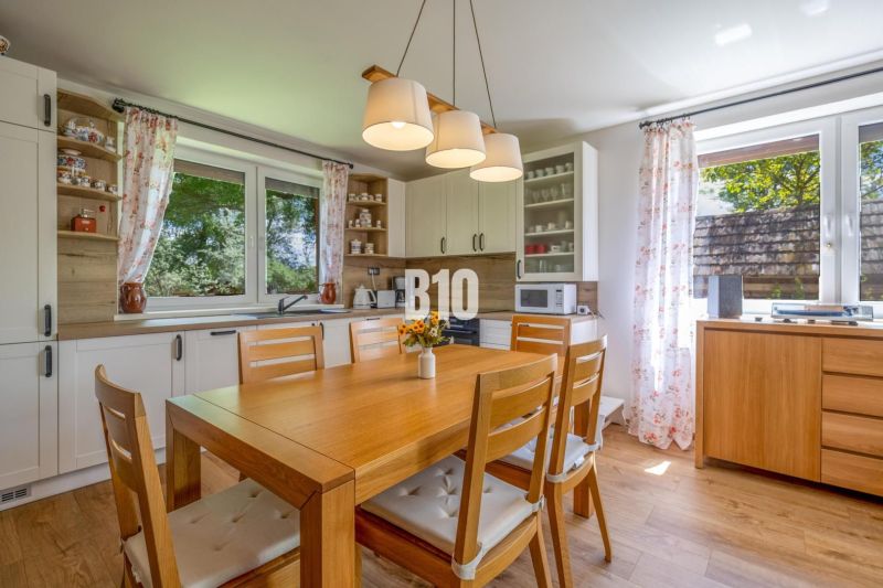 A kitchen in a family house with a wooden table and decor, in light colors.