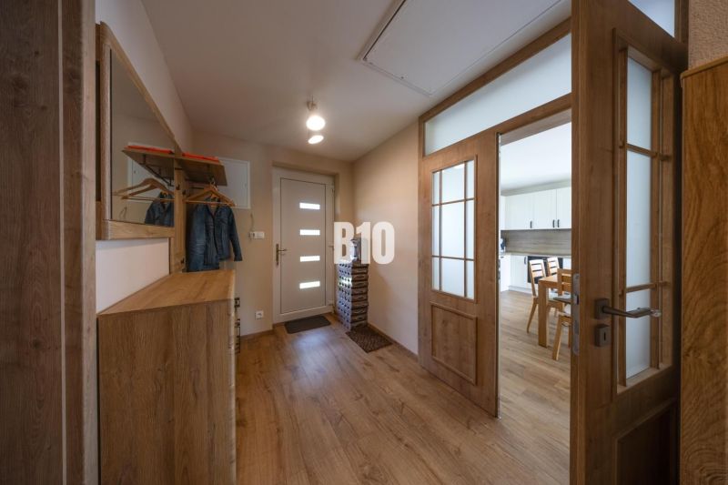 Entrance hall with a wardrobe and a mirror in a family house, floor with wooden decor.