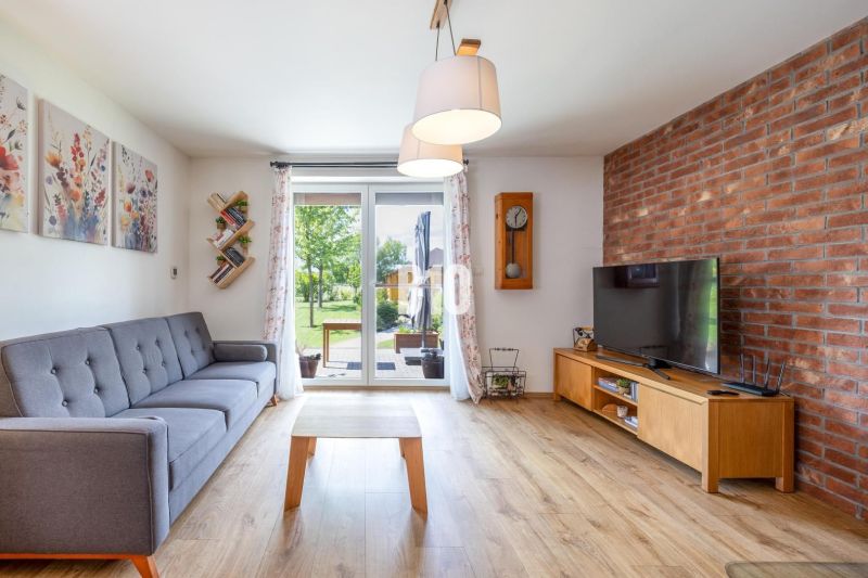 Living room in a family house with a brick wall, comfortable sofa, and wooden decor flooring.