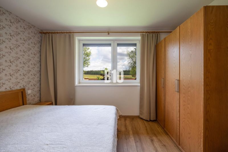 Bedroom with wood-patterned flooring and a view from the window in a family house.
