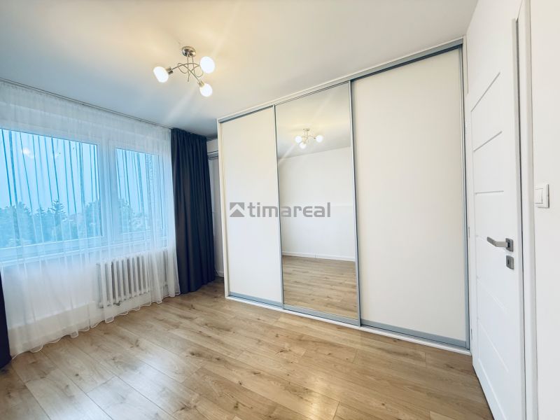 A bright room in a 3-room apartment with a wooden decor floor and a built-in wardrobe.