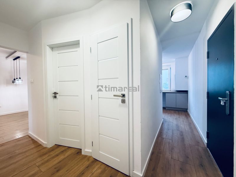 A hallway in a 3-room apartment with a wooden decor floor and white doors.