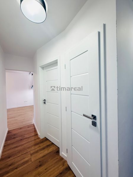 A hallway in a 3-room apartment with white doors and a floor with a wood design.