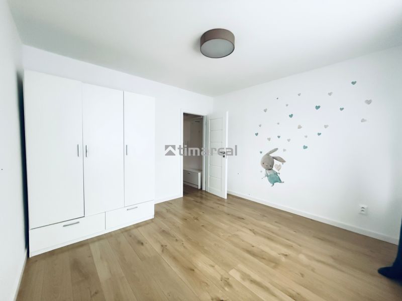 Children's room in a three-room apartment with a wood-patterned floor and white furniture.