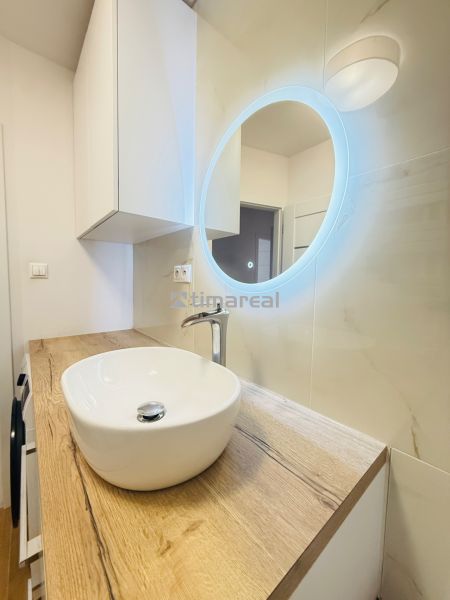 A bathroom in a 3-room apartment with a designer sink and illuminated mirror.