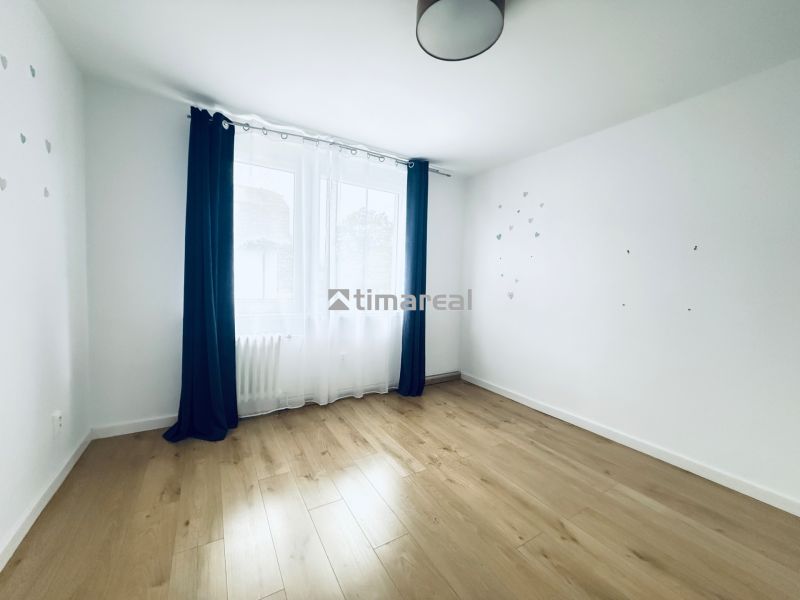 A bright room with a wooden decor floor and dark curtains in a 3-room apartment.