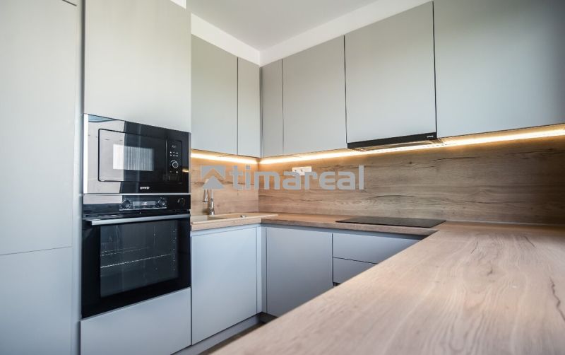 A kitchen in a 3-room apartment with a wood-patterned floor and built-in appliances.