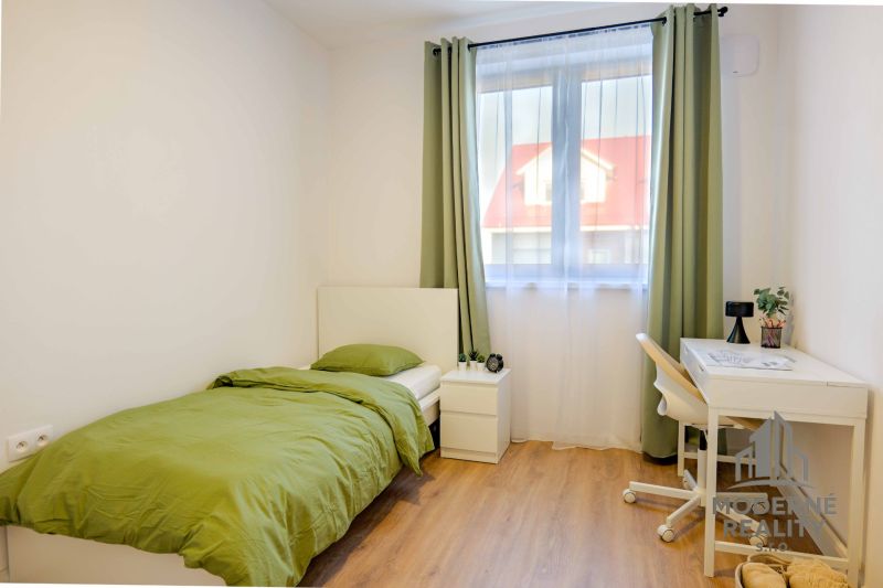 A simple room with green bedding and a wood-patterned floor.