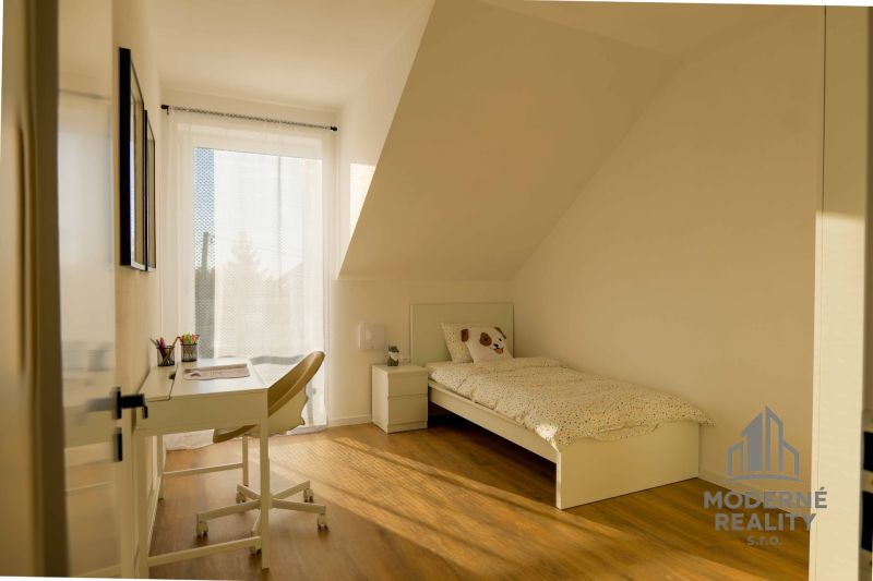 A room in a family house with a bed, a desk, and a floor with a wooden decor.