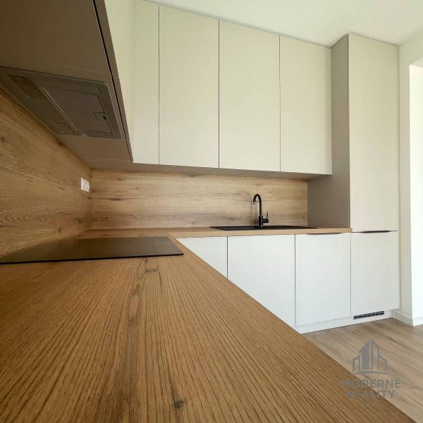 A kitchen in a family house with an elegant wooden decor floor and white cabinets.
