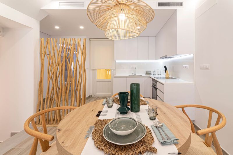 Dining area in a holiday apartment with wooden decorative elements and a ceiling light.