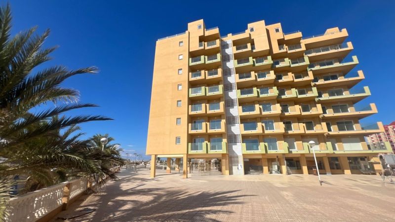 Recreational apartment in La Manga del Mar Menor with palm trees and a clear sky.