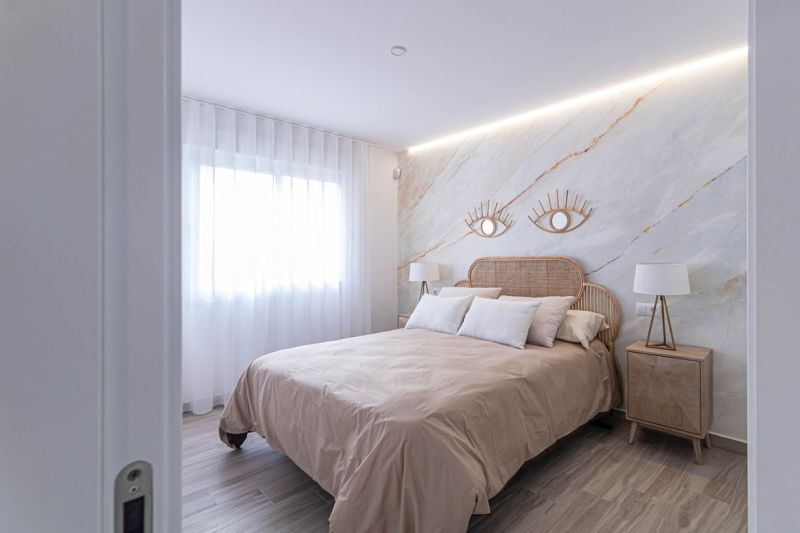 A bedroom in a holiday apartment with a bed, fabric curtains, and a wooden decor floor.
