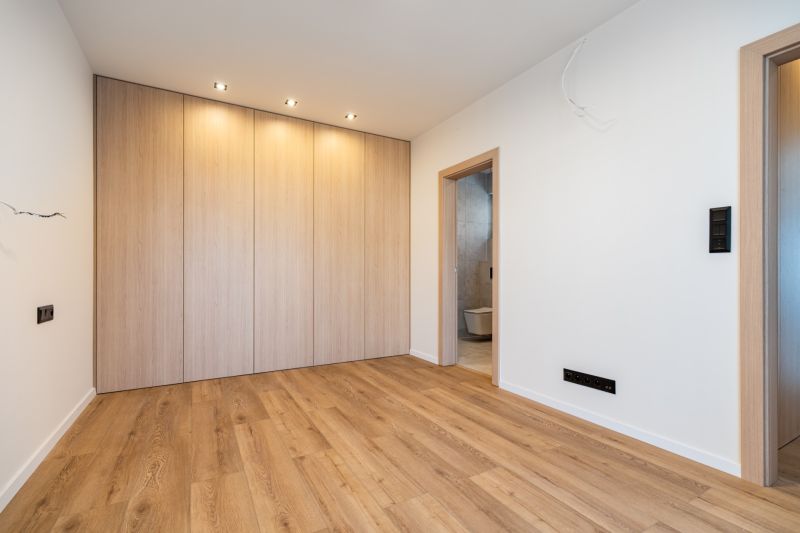 A room in a family house with a wooden decor floor and a built-in wardrobe.