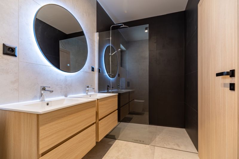 A bathroom in a family house with two sinks and round mirrors with LED lighting.