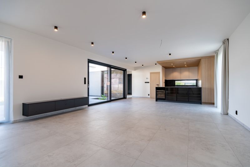 Living room in a family house with a kitchen unit and large glass doors.