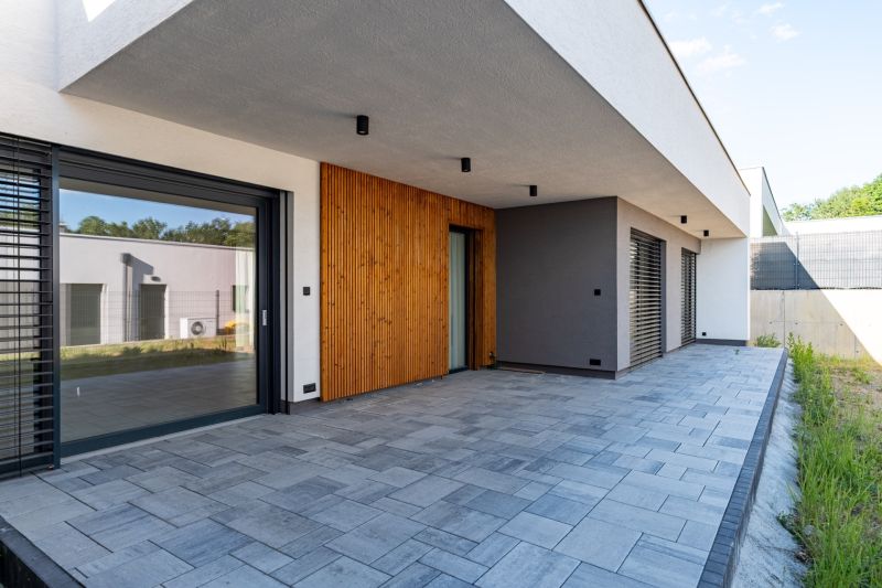 A family house in the Košice area with a terrace, wooden cladding, and paving.