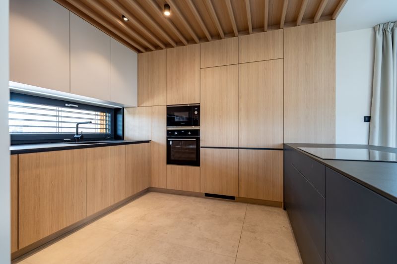 A kitchen in a family house with wooden cabinets and a black countertop.