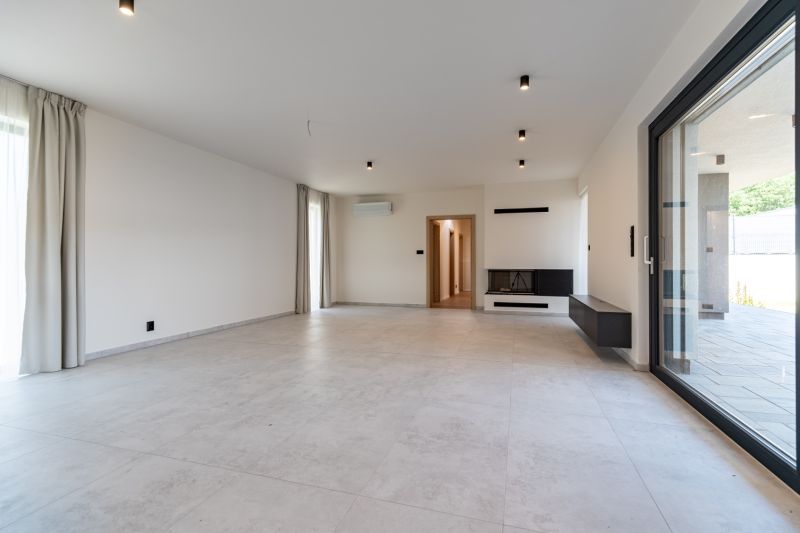 A living room in a family house with a light floor and a fireplace.
