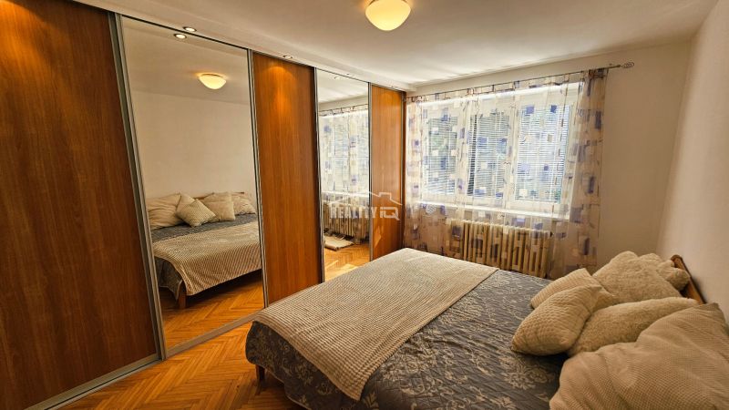 A bedroom with wardrobes with sliding doors and a large mirror in a 2-room apartment.