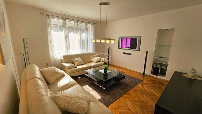 Living room with a white sofa and a wooden decor floor in a 2-room apartment.