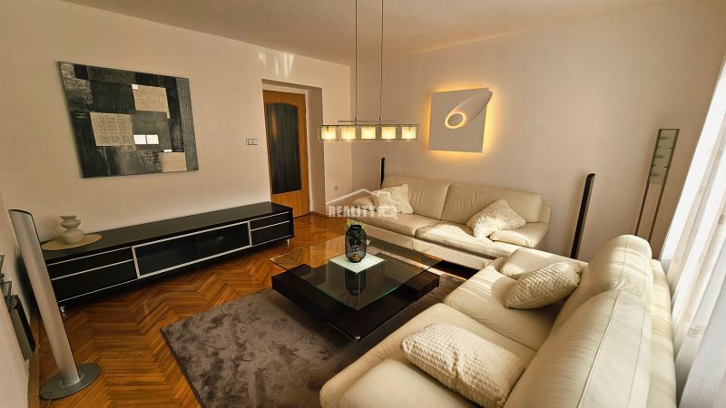 Living room with a leather sofa, glass table, and wood-patterned flooring in a two-room apartment.