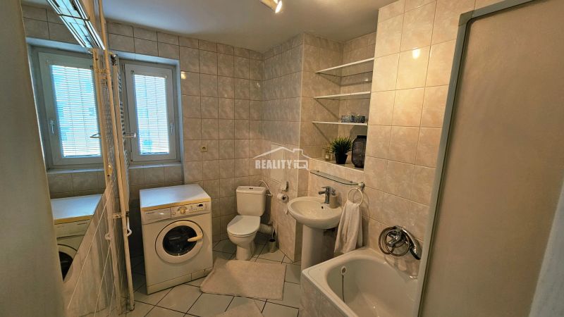 Bathroom with a bathtub, shower, washing machine, and sanitary facilities in a 2-room apartment.