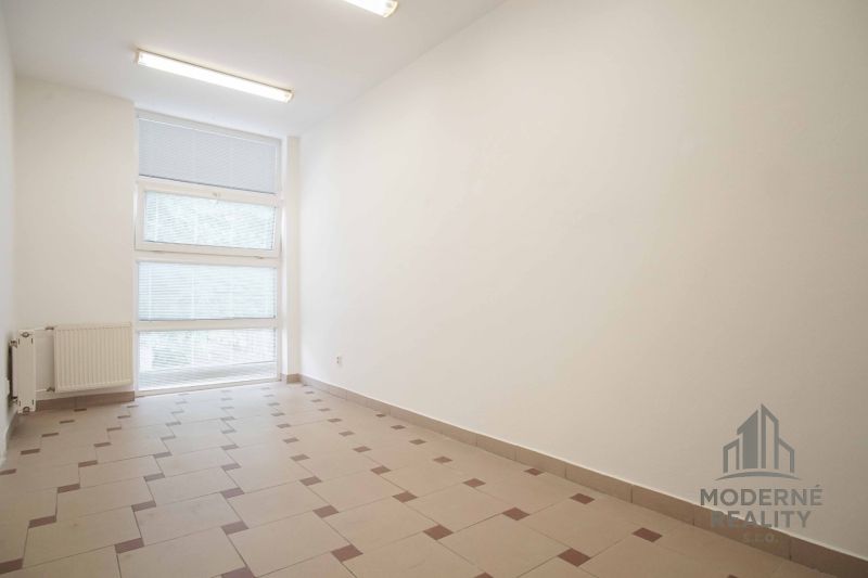White office with tiles, large window, and radiator.