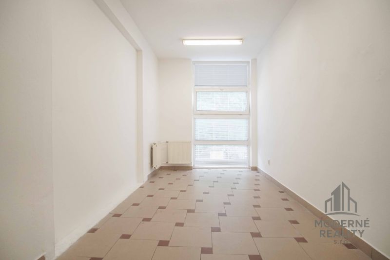 Office interior with a window and a radiator, tiled floor.
