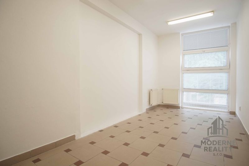 The interior of an office with large windows and light-colored tiles on the floor.