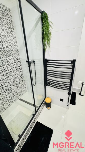 Bathroom with a shower and black-and-white decorations in a studio apartment.