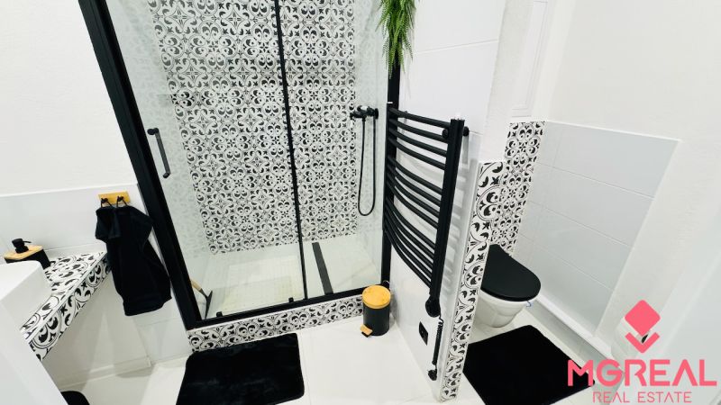 A bathroom with a shower and black-and-white patterns in a studio apartment.