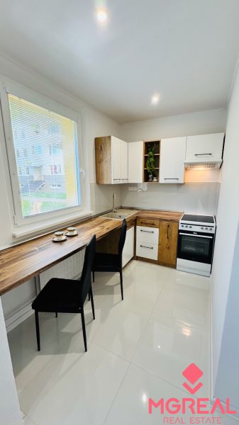 A kitchen in a studio apartment with white cabinets and a wood-patterned floor.