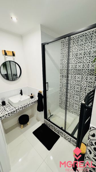 A bathroom in a one-room apartment with black and white tiles and a shower corner.