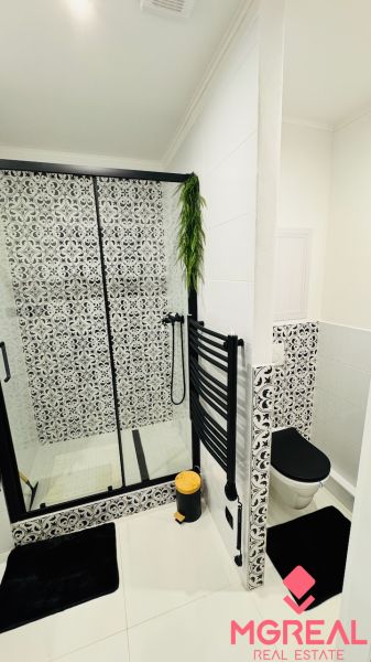 A bathroom in a studio apartment with black and white tiles and hanging greenery.