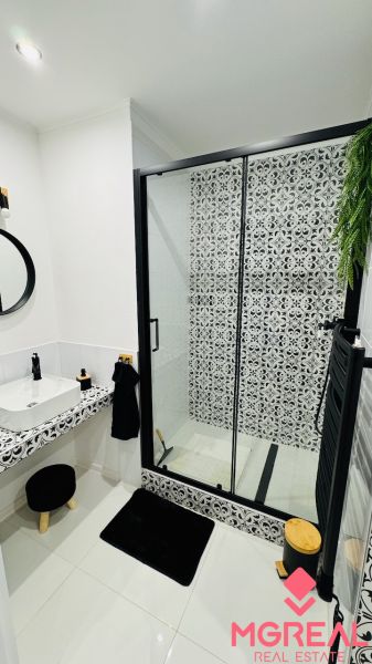 Bathroom with a shower and patterned tiles in a studio apartment.