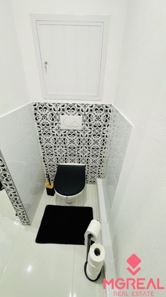 A toilet with a black-and-white tile pattern in a studio apartment.
