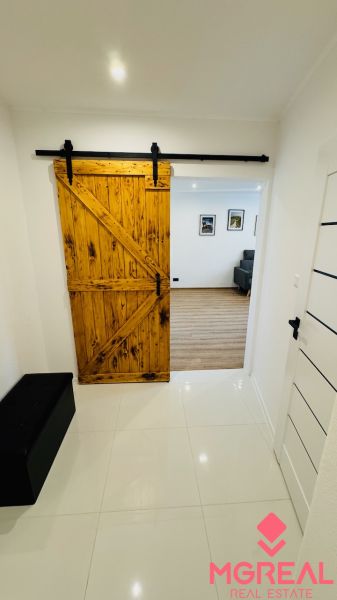 Interior with sliding wooden doors leading to a studio apartment with wood-patterned flooring.