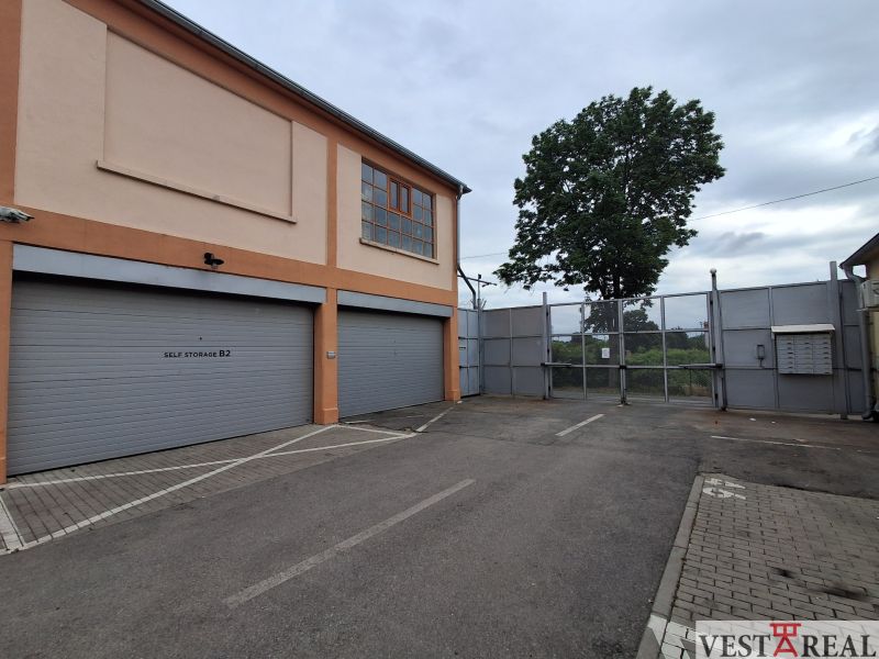 The exterior of the warehouse and halls on Coburgova Street in Trnava, with large gates and a tree.
