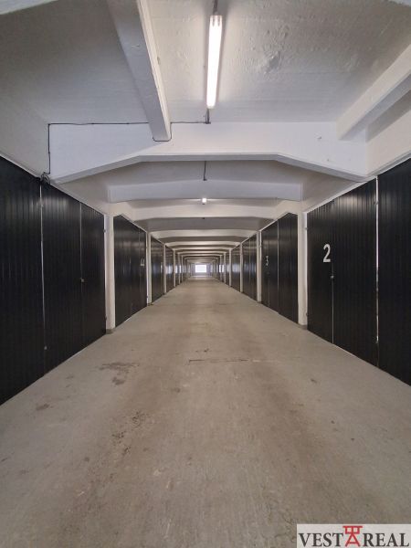 Narrow corridor with numbered sections in warehouses and halls, illuminated by fluorescent lights.