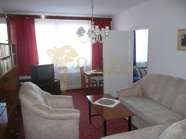 Living room in a two-room apartment with a red carpet and a beige sofa.
